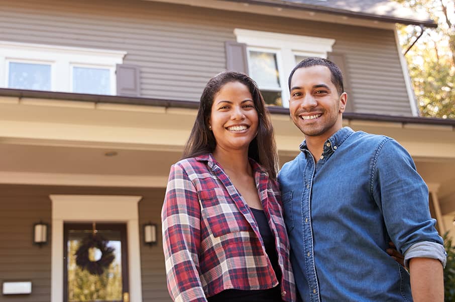 smiling black couple in front of home