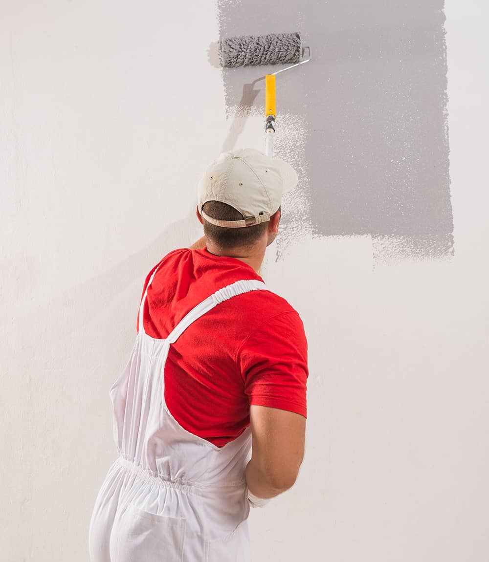 young man on painting wall with roller