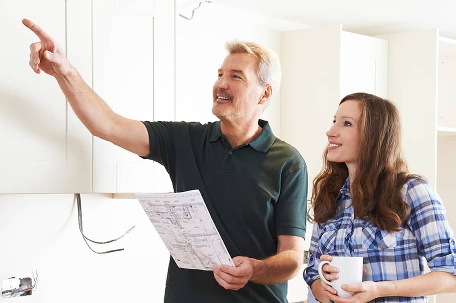 contractor pointing to cabinets with smiling homeowner
